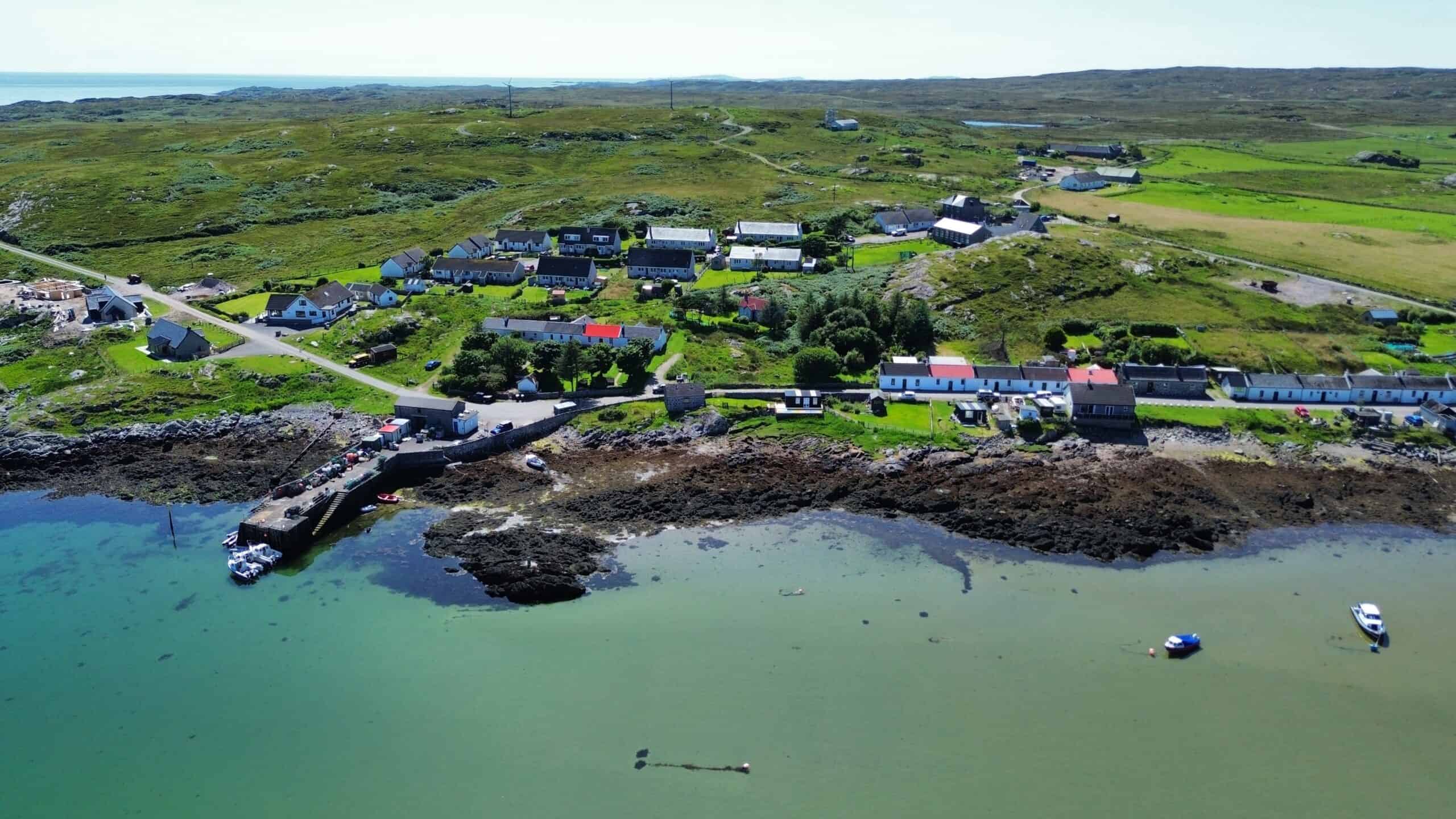Aerial view of a scenic seaside village with boats and lush green surroundings, perfect for Wee Trails.