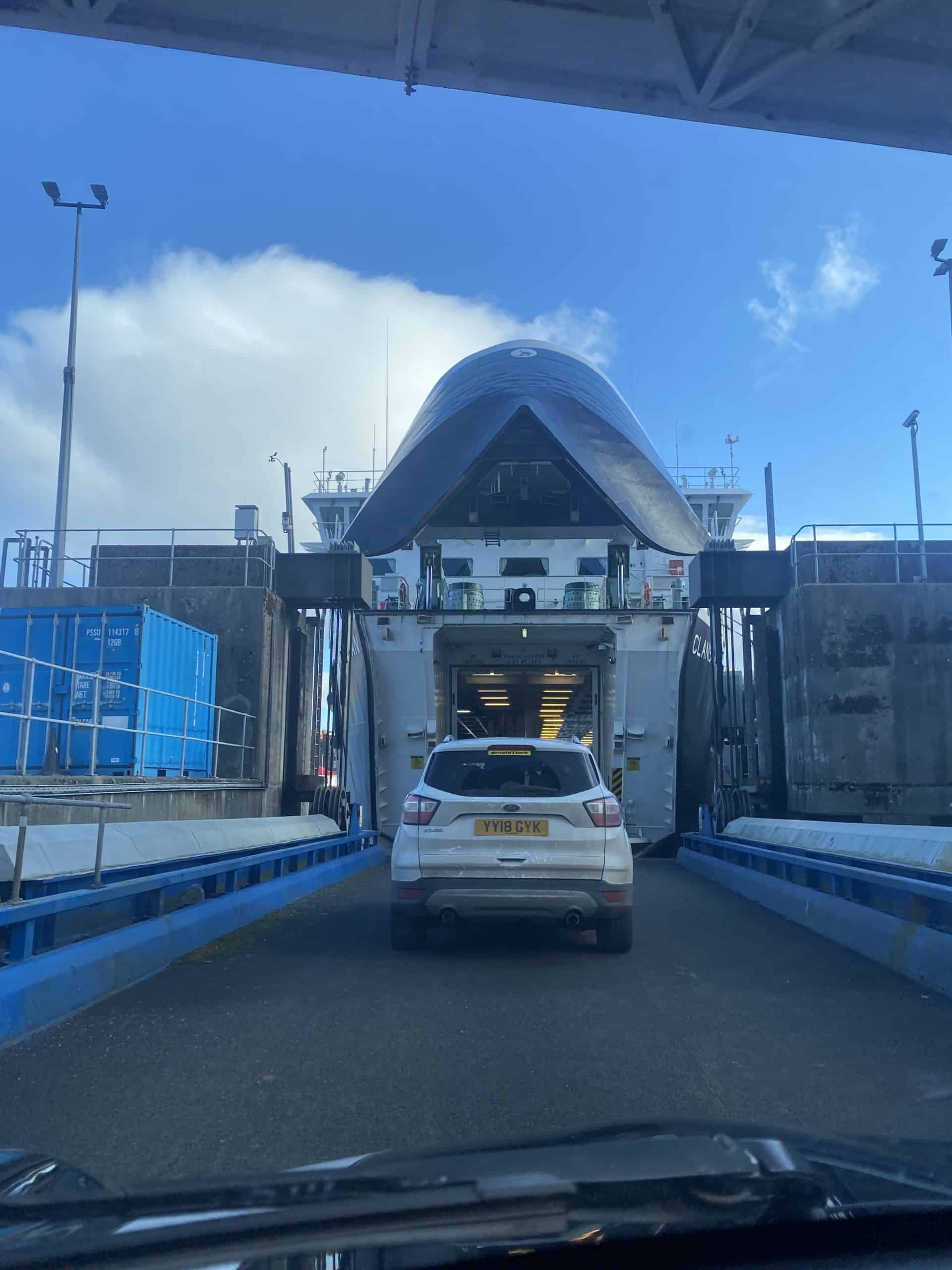 Ferry loading car at terminal with a futuristic design, bright blue sky, and maritime transport.