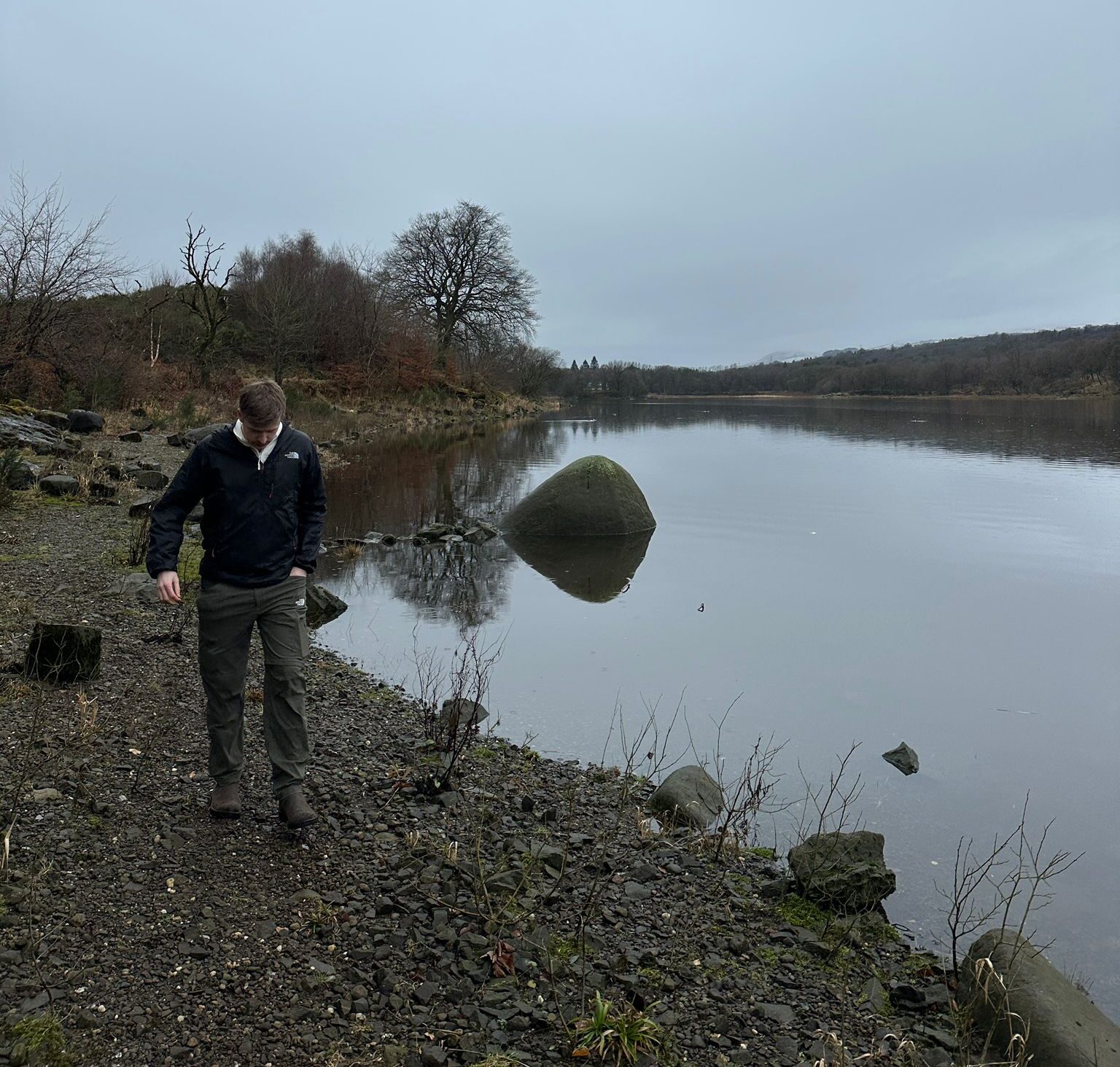 Lakeside walk with a person enjoying the peaceful scenery by the water.